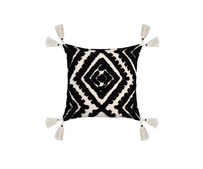 Black and white geometric patterned cushion with tassels at each corner.