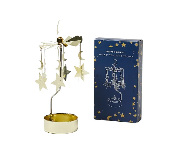 Oliver Bonas rotary tealight holder with star and moon design next to its decorative packaging.