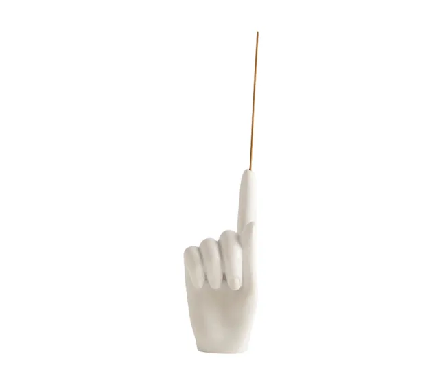 A ceramic hand-shaped incense holder with an incense stick pointing upward.