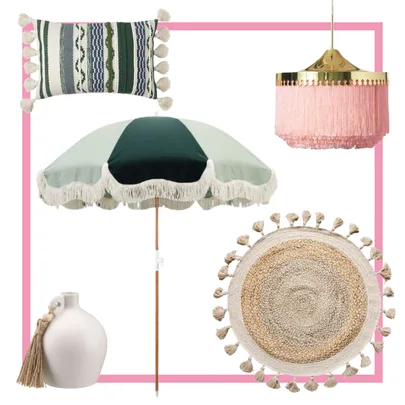 Decor items including a fringe umbrella, woven cushion, pink lamp, tassel vase, and round jute rug with tassels.