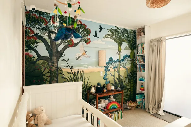 Children's room with a nature-themed mural, crib, toys, books, and hanging mobile.
