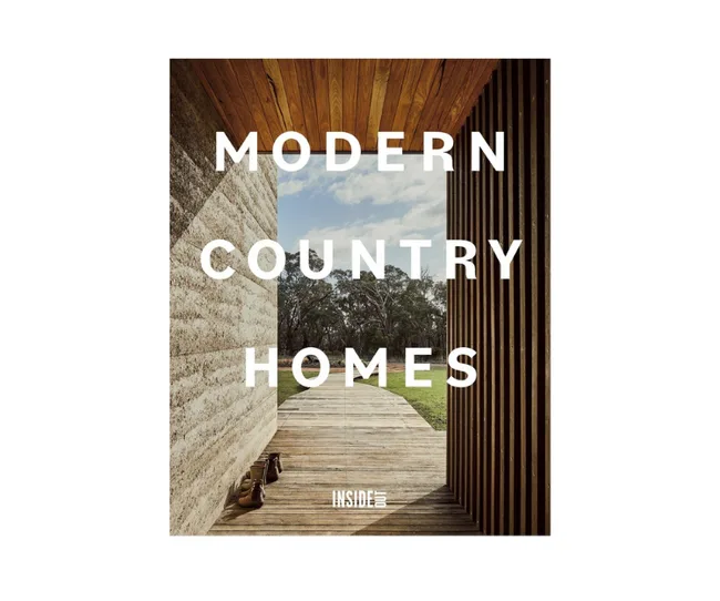 Modern country home with wooden exterior, open view of trees, and blue sky. Text reads "Modern Country Homes."