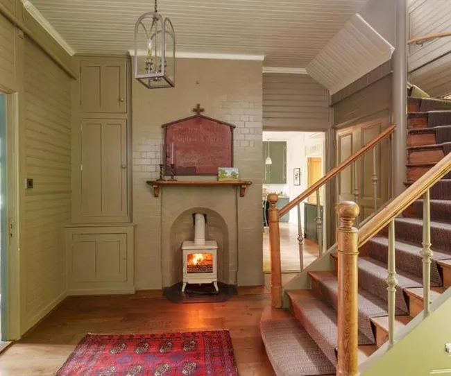 Staircase and fireplace in a rustic home interior with green walls and a wooden floor.