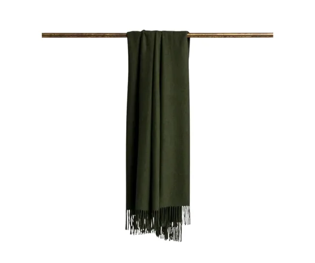 Dark green scarf with fringed edges hanging on a wooden rod against a white background.