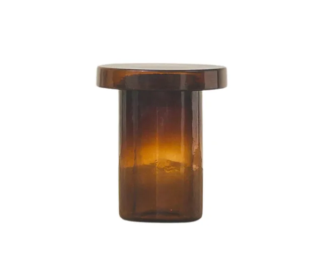 A brown glass jar with a flat, round lid, illuminated from inside, on a white background.