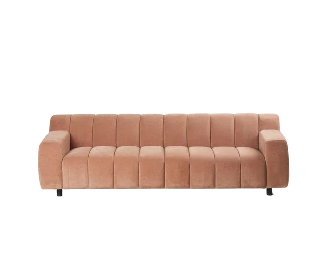 Pink velvet sofa with vertical tufted pattern, wide armrests, and black legs on a white background.
