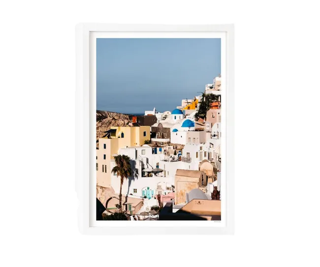 Framed photo of Santorini's white and pastel buildings with blue domes under a clear sky.