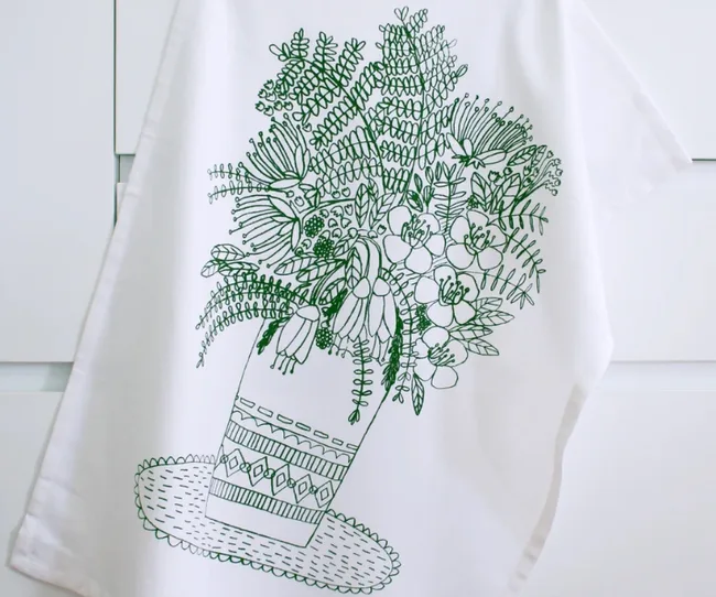 Line drawing of a vase with various flowers on a white cloth hanging against a light background.