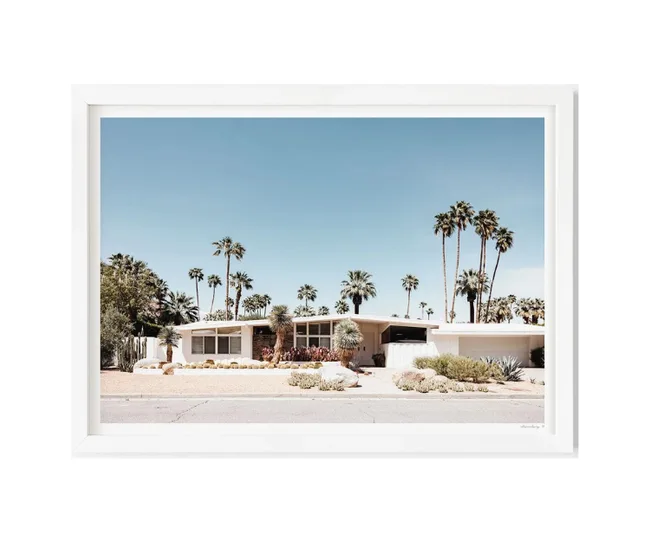 Mid-century modern house with palm trees under a clear blue sky, framed in white.