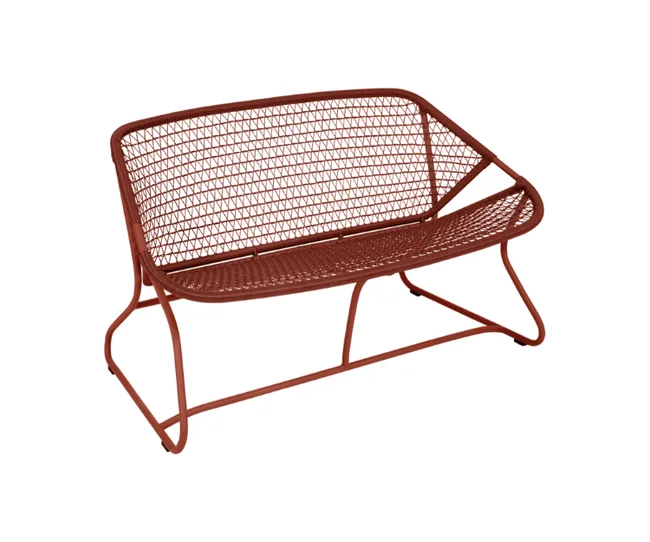 Red metal mesh loveseat with geometric design and angled legs against white background.
