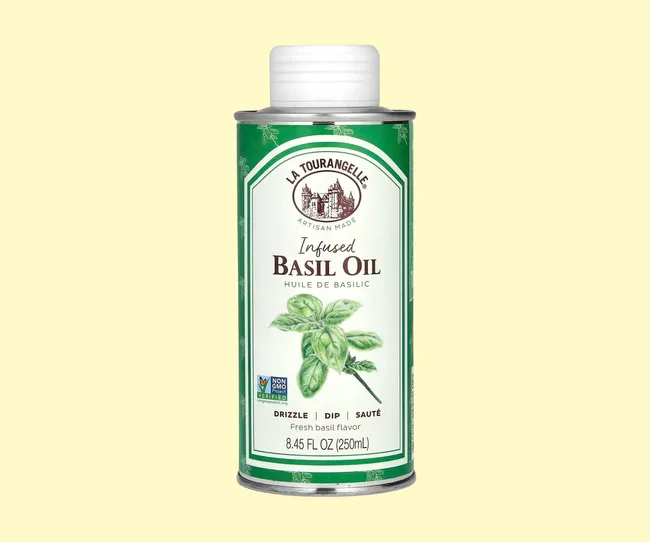 A green bottle of basil oil against a yellow background