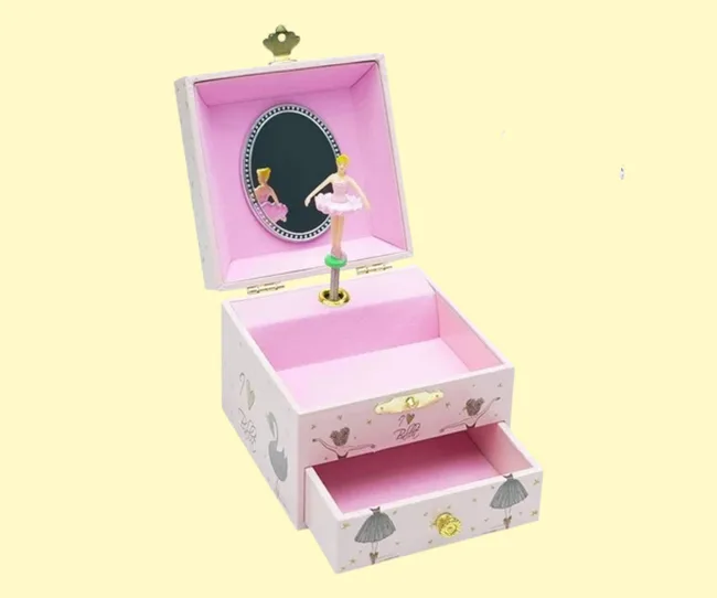 A pink jewellery box with a ballet dancer in it against a yellow background