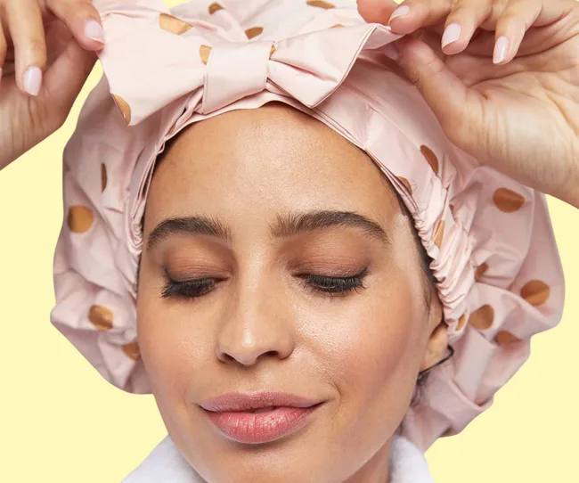 A woman wearing a pink showercap with brown polka dots