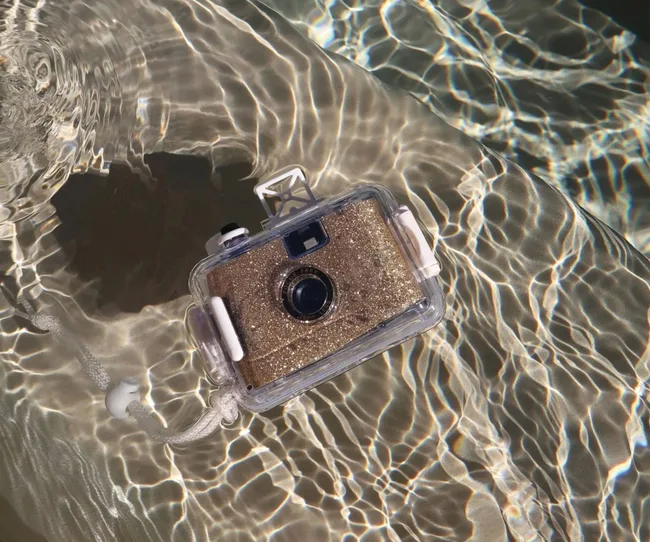 A gold sparkly camera lying in water