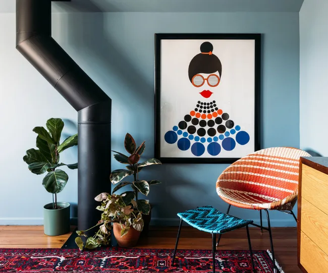 Stylish room with a modern art poster, plants, a woven chair, and a wooden cabinet on a patterned rug.