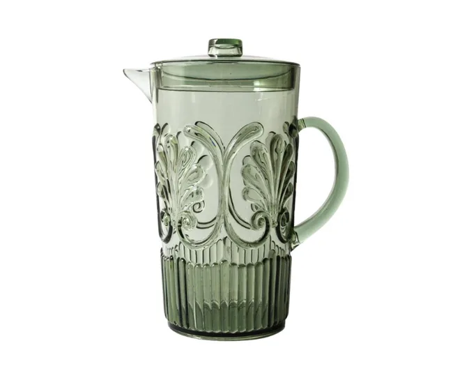 Green glass pitcher with ornate floral patterns and a handle, featuring a lid and spout, placed against a white background.