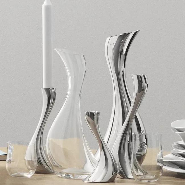 Curved silver and clear glass vases and candle holders on a wooden surface.