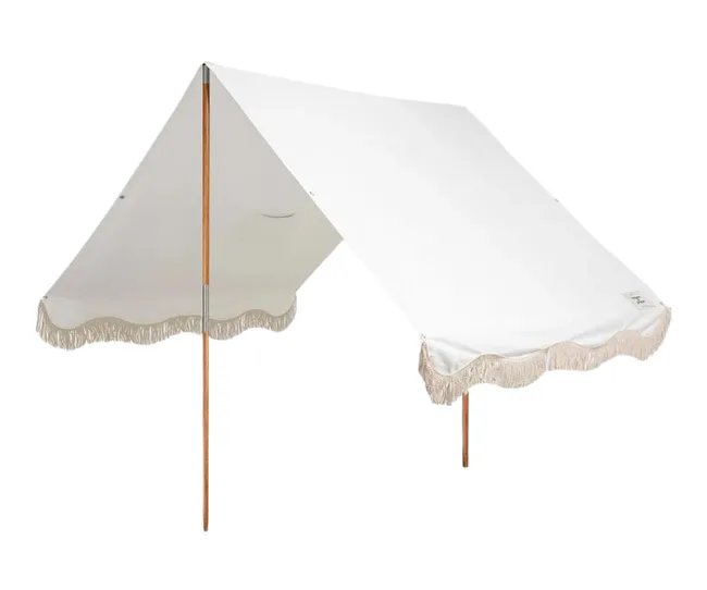 White canopy with wooden poles and fringe trim along the edges, set against a plain background.