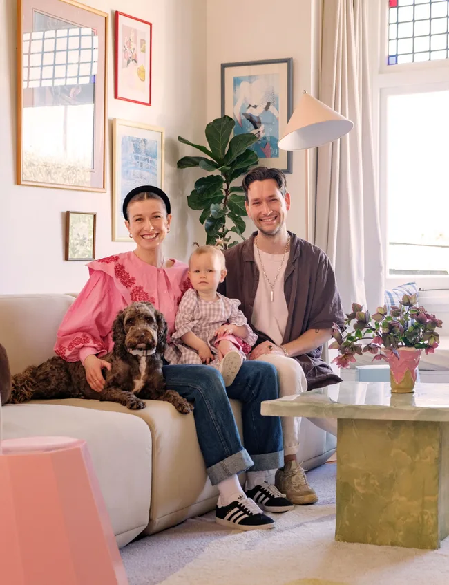 Family sitting on a couch in a cozy living room with a dog, child, and decor.