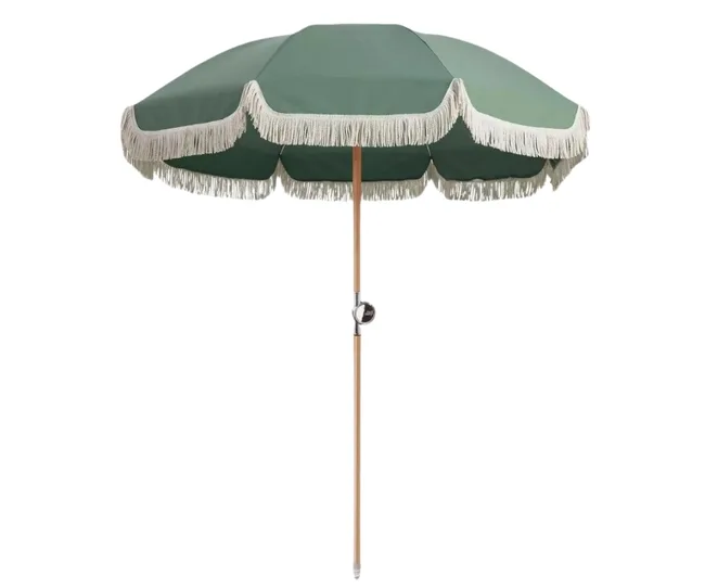 Green patio umbrella with a fringed trim, wooden pole, and crank handle, fully open against a white background.
