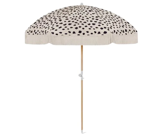 Dalmatian print beach umbrella with a wooden pole on a white background.