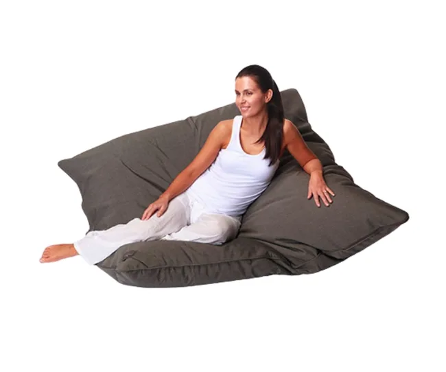 A woman in casual clothes relaxing comfortably on a large gray bean bag chair.