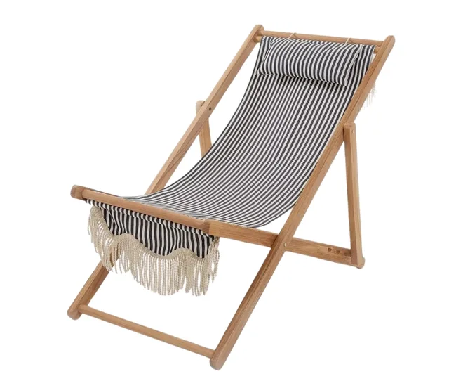 A wooden deck chair with black and white striped fabric and fringe details.