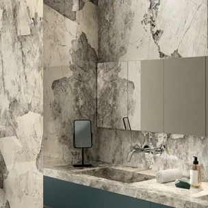 Marble-themed bathroom with a modern faucet, vanity mirror, rolled towel, and soap dispenser.
