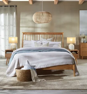 Bedroom with wooden bed, striped bedding, wicker basket, rattan light fixture, and side tables with lamps.