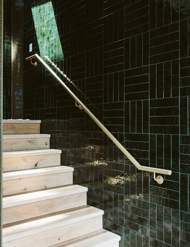 A timber stairwell with deep green tiles on the wall