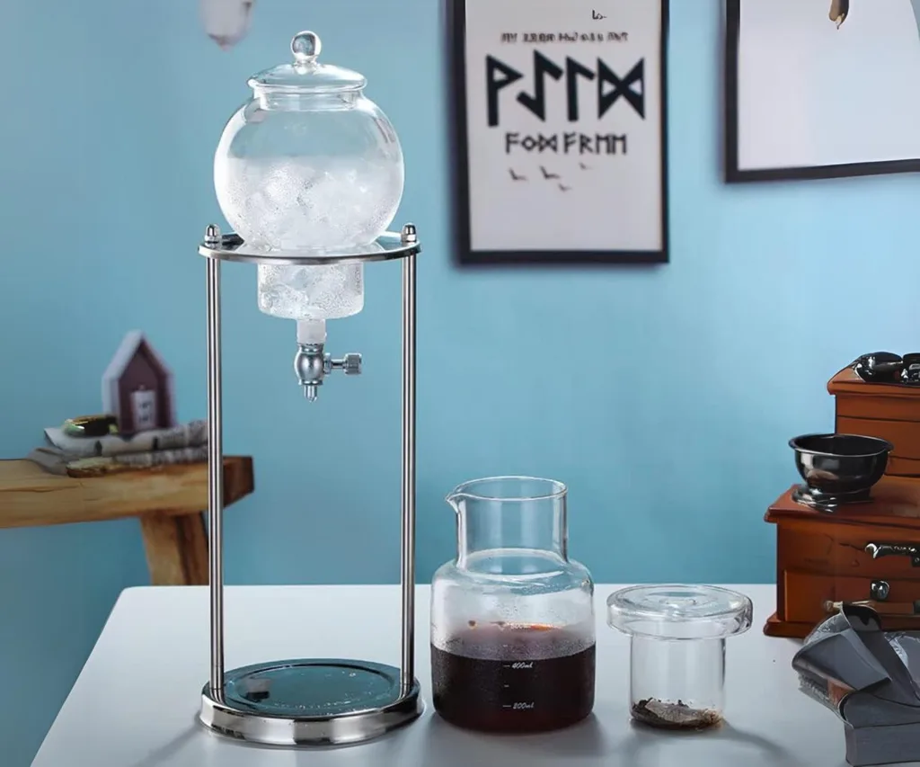 Cold brew coffee drip tower with glass containers and metal stand on a table.