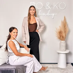 Two women smiling in a modern room, one seated and one standing, with "BO & KO baby" on the wall.