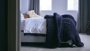Blue weighted knit blanket on bed