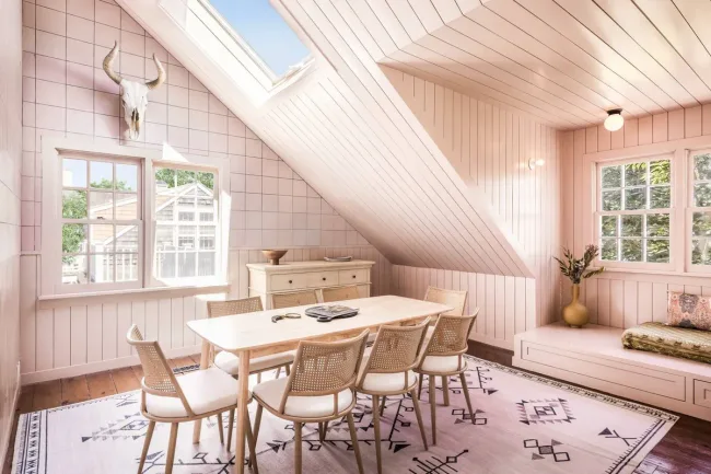 Bright dining room with skylight, wooden table, and six chairs, adorned with a bull skull wall decor.