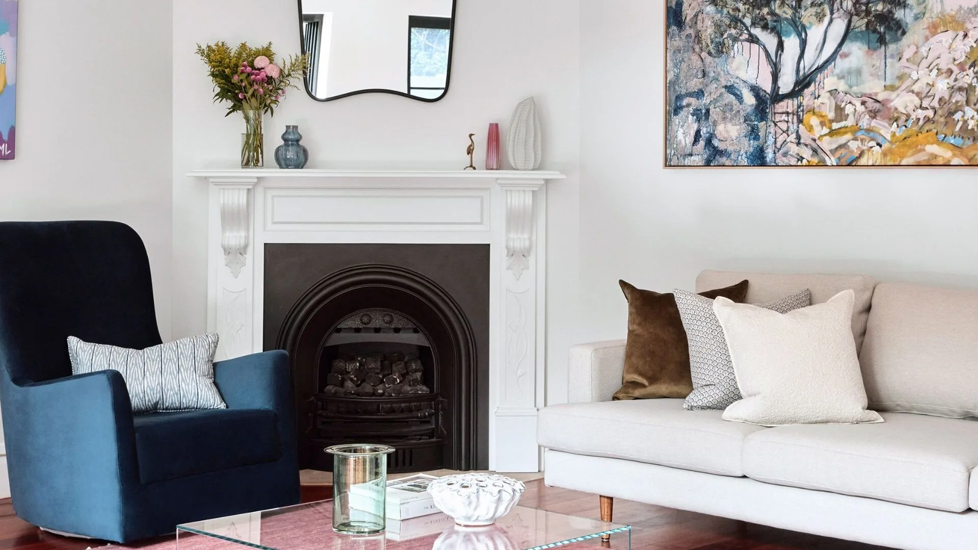 A living room wuth a fireplace in the corner and a bright pink rug on the floor