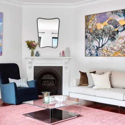 A living room wuth a fireplace in the corner and a bright pink rug on the floor