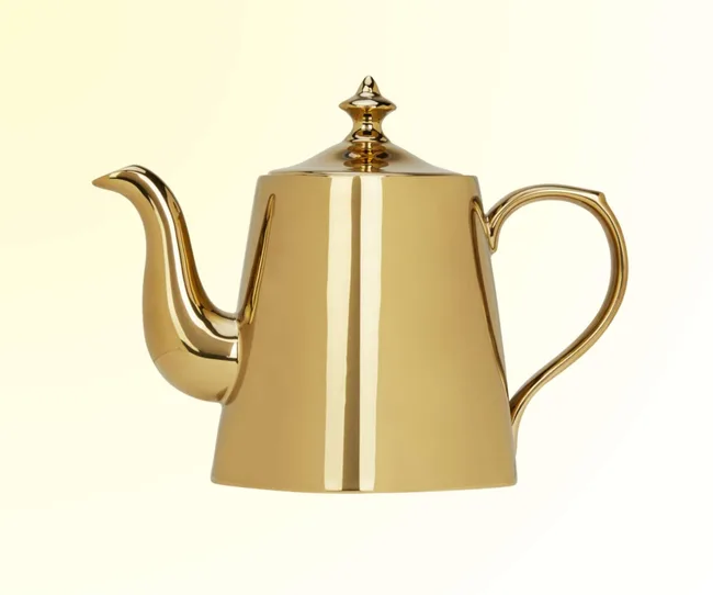 A gold teapot against a yellow background.