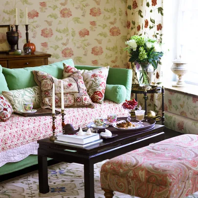 Floral-themed living room with a green sofa, patterned cushions, and a coffee table set with tea and snacks.