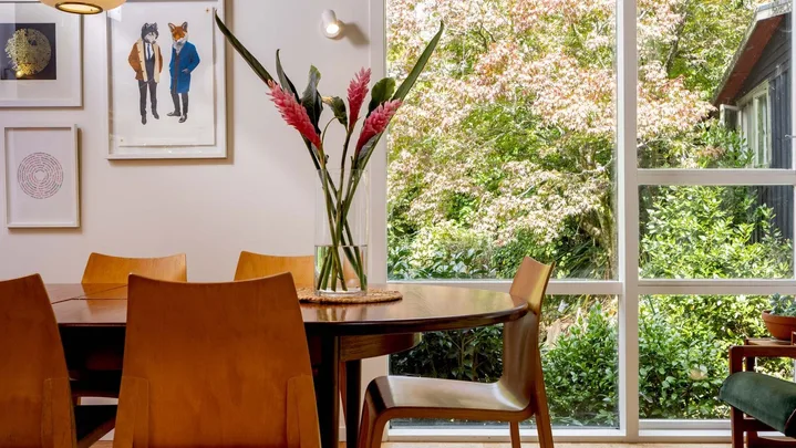 Dining room table with wooden chairs around it and a vase in the middle