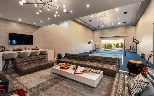 Luxurious recreation room with seating, table tennis, guitars, TV, and modern lighting.