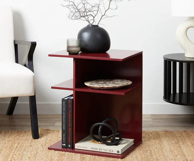 Burgundy side table holding books and home decor