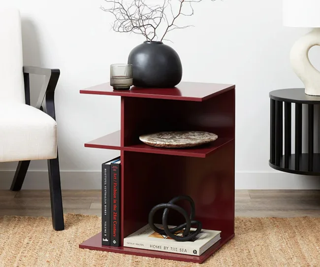 Burgundy side table holding books and home decor