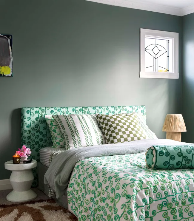 A green themed bedroom with dark green walls and lime green bedding