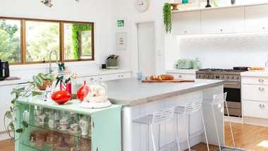 A white and green kitchen with an island in the foreground