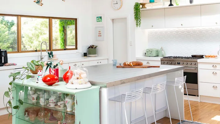 A white and green kitchen with an island in the foreground