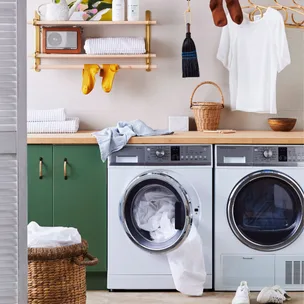 Laundry room with a washer and dryer, green cabinets, shelves with towels, radio, and hanging clothes.