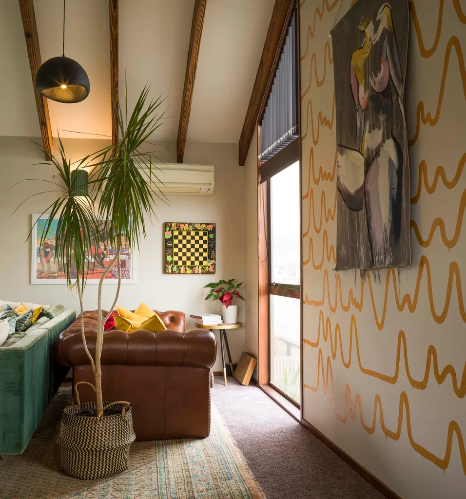 Squiggly lined yellow wallpaper leading to the living room, with brown leather couches