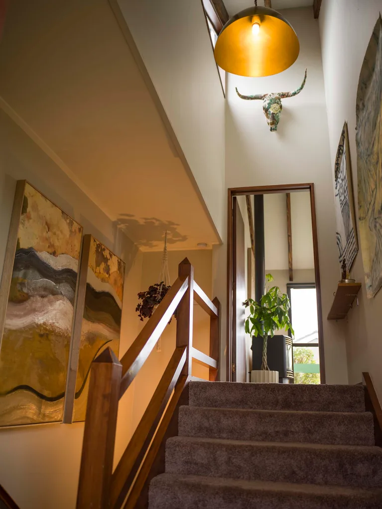 A carpeted stairwell with art hanging up the walls