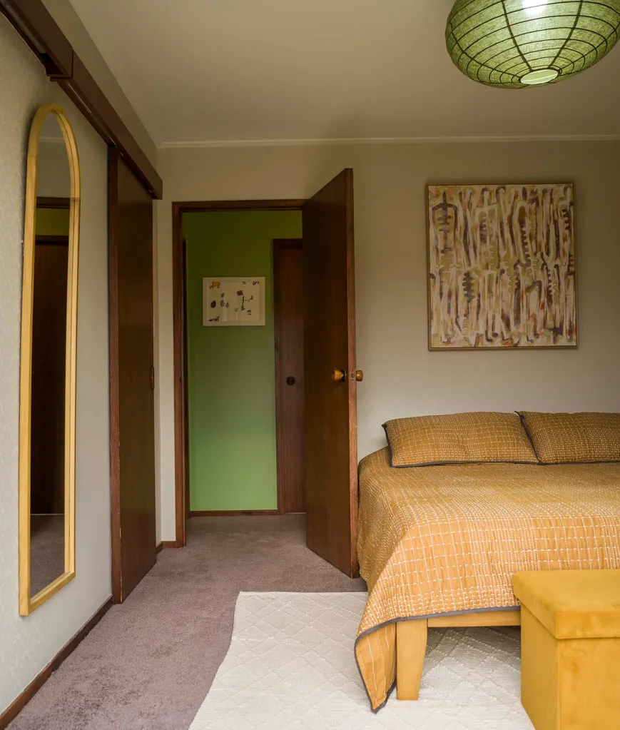 The master bedroom with a mustard duvet cover and pillow cases over the bed