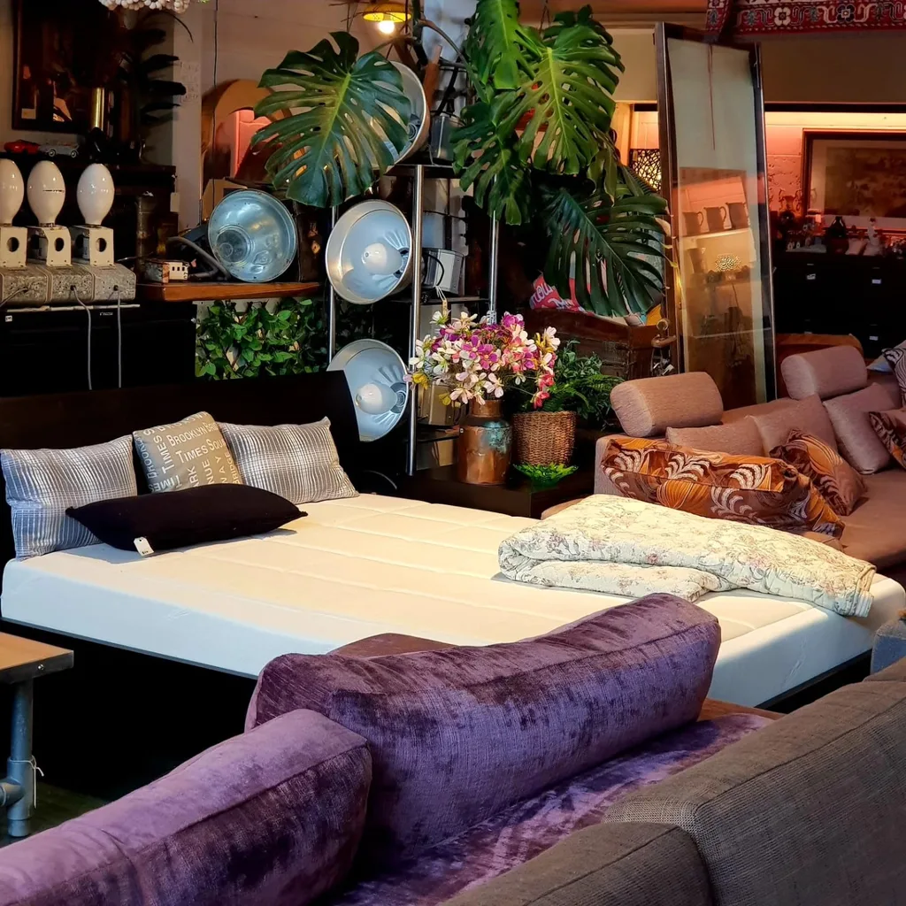 A display of a second-hand bed, set of lights and a pink sofa within Glenfield Furniture store.
